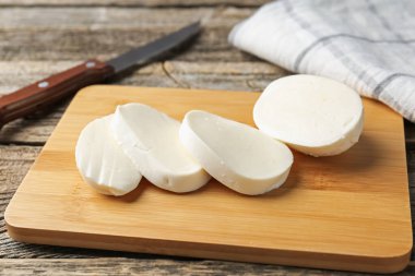 Ahşap masada mozarella peyniri ve bıçak kes, yakın plan.