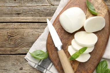 Ahşap masada fesleğen ve bıçakla mozzarella peyniri kes. Metin için boşluk