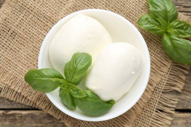 Ahşap masada lezzetli mozzarella peyniri ve fesleğen.