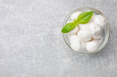 Açık gri masada Mozzarella peynirli toplar ve fesleğen, üst manzara. Metin için boşluk