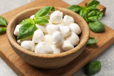 Mozzarella peynir topları ve fesleğen açık gri masada, yakın plan.