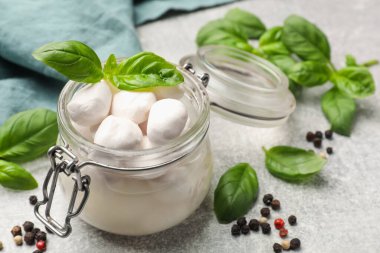 Açık gri masada fesleğenli ve biberli Mozzarella peynir topları, yakın plan.