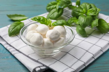 Mozzarella peynir topları ve fesleğen mavi ahşap masada, yakın plan.