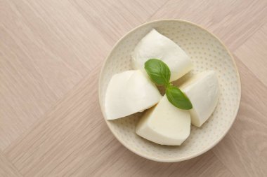 Ahşap masadaki fesleğen ve mozzarella peyniri parçaları, üst manzara. Metin için boşluk