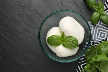 Lezzetli mozzarella peyniri ve fesleğen parçaları koyu dokulu masada, düz yerde. Metin için boşluk