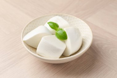 Nefis mozzarella peyniri ve fesleğen parçaları ahşap masada, yakın plan.