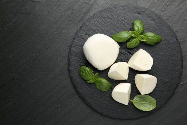 Lezzetli mozzarella peyniri ve fesleğen parçaları koyu dokulu masa, üst manzara. Metin için boşluk