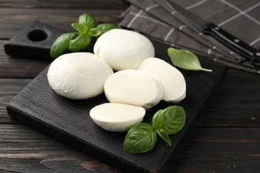 Nefis mozzarella peyniri ve fesleğen parçaları ahşap masada, yakın plan.