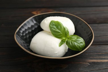 Nefis mozzarella peyniri ve fesleğen parçaları ahşap masada, yakın plan.