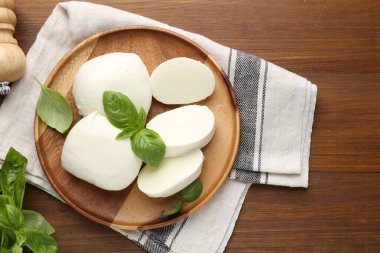 Lezzetli mozzarella peyniri ve fesleğen yaprakları ahşap masada, düz yerde.
