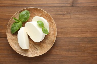 Ahşap masa üzerinde lezzetli mozzarella peyniri ve fesleğen yaprakları, üst manzara. Metin için boşluk