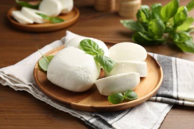 Nefis mozzarella peyniri parçaları ve fesleğen yaprakları ahşap masada, yakın plan.