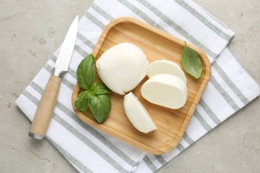 Lezzetli mozzarella peyniri parçaları, fesleğen yaprakları ve bıçak gri desenli masa, üst manzara