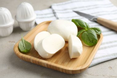 Lezzetli mozzarella peyniri ve fesleğen yaprakları. Gri desenli masa, yakın plan.