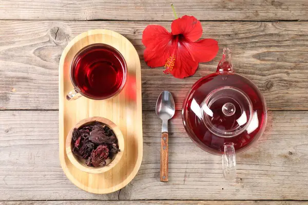 Cam fincanda leziz amber çayı, çaydanlık, kuru gül sepals ve tahta masada çiçek, düz uzanmış