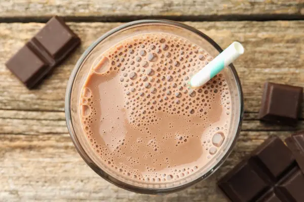 Lezzetli çikolatalı süt cam ve parçalar ahşap masada, düz yatıyordu.