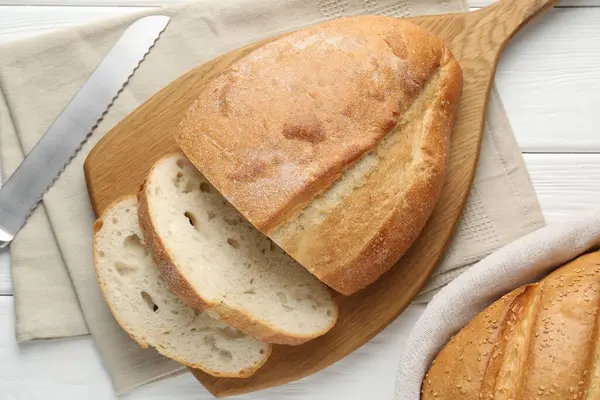 Beyaz ahşap masada ekmek ve bıçak kes, düz uzan.