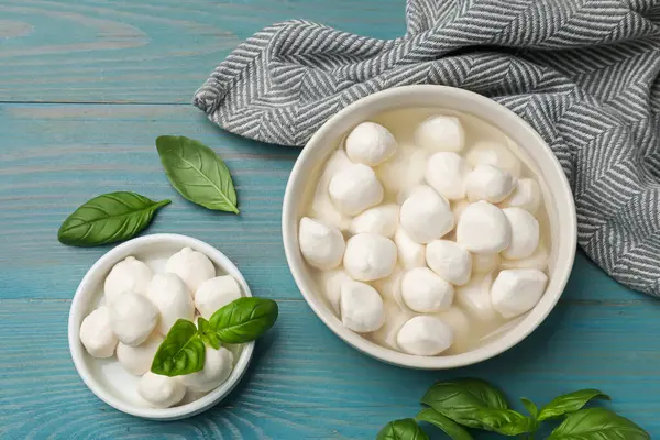Mozzarella peyniri topları ve fesleğen mavi ahşap masada, düz yatıyordu.