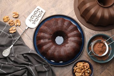 Lezzetli çikolatalı kek, ceviz ve kakao tozu ahşap masada, düz uzanmış