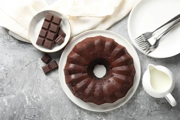 Lezzetli kek, çikolata ve süt parçaları gri masada, düz uzanmış.