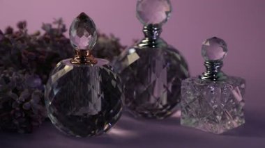 Parfüm şişeleri ve mor arka planda güzel leylak çiçekleri, yakın plan. Işığın yönü değiştiriliyor