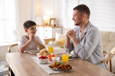 Baba ve oğul akşam yemeğinden önce evde dua ediyorlar.