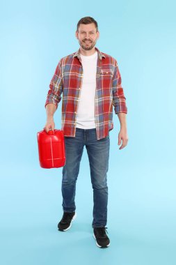 Açık mavi arka planda plastik kutu tutan adam.