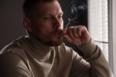 Odada sigara içen bir adam var.