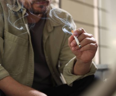 Arka planda sigara içen adam, yakın plan.