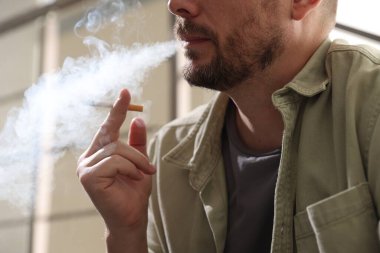 Arka planda sigara içen adam, yakın plan.