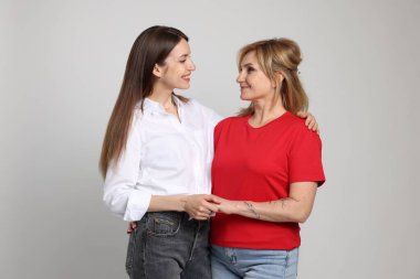 Açık gri arka planda annesine sarılan bir kadın.