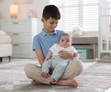 Evde yerde oturan sevimli küçük kardeşler.