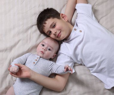 Yatakta sevimli küçük kardeşler, üst manzara.