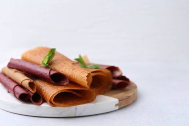 Lezzetli meyve dürümleri ve nane şekeri ışık masasında, yakın plan. Metin için boşluk