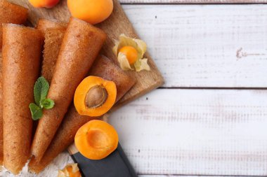 Lezzetli meyve dürümleri, kayısılar ve beyaz ahşap masa üzerinde bitki salatası, düz yatak. Metin için boşluk