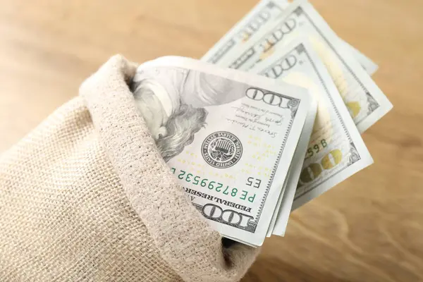 Tahta masanın üzerinde dolar banknotları olan çanta, yakın plan.