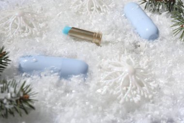 Nemlendirici dudak kremleri, Noel dekorasyonu ve yapay kar üzerindeki köknar ağacı dalları, yakın plan. Kış bakımı