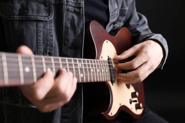 Siyah arkaplanda gitar çalan adam, yakın plan