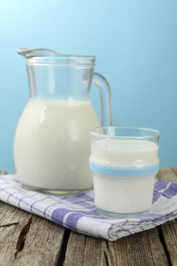 Açık mavi arka planda, ahşap masada taze süt, yakın plan.