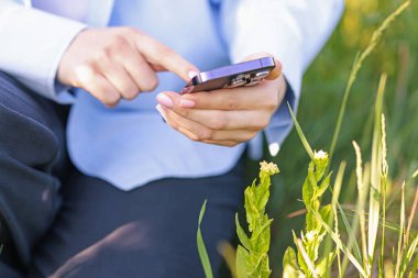 Açık havada akıllı telefondan bitki tanıma uygulaması kullanan bir kadın.
