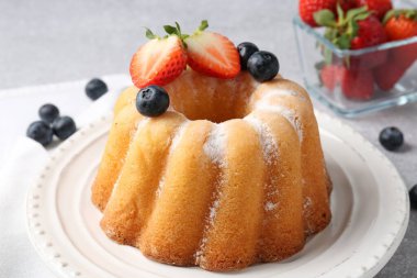 Açık gri masada pudra şekeri ve böğürtlenli Lezzetli kek, yakın plan.