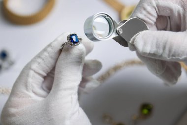 Loupe 'a değer biçen, beyaz masada lüks yüzük değerlendirmesi yapan bir eksper.