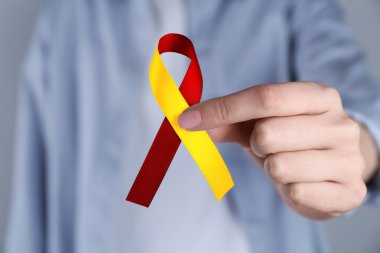 Dünya Hepatit Günü. Sarı-kırmızı farkındalık kurdeleli kadın, yakın plan.