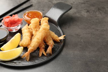 Lezzetli tempura karidesleri, limon, zencefil ve soslar gri desenli masa, yakın plan. Metin için boşluk