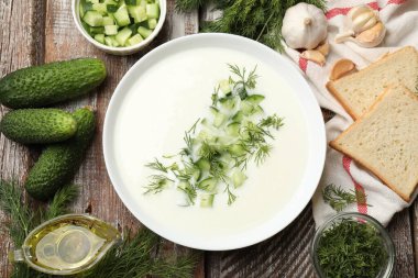 Lezzetli salatalık çorbası kasede ve ahşap masada malzemeler.