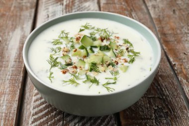 Ahşap masada dereotlu ve fındıklı leziz salatalık çorbası.
