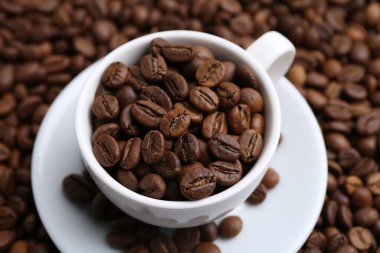 Kahve çekirdekleri üzerinde fincan ve çay tabağı.