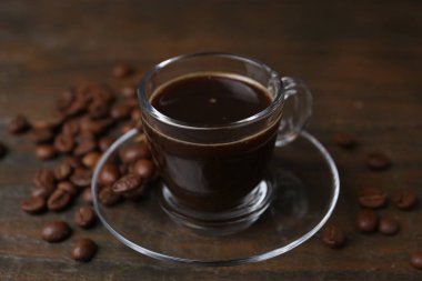 Cam bardakta Aromatik kahve ve ahşap masada fasulye, yakın plan.