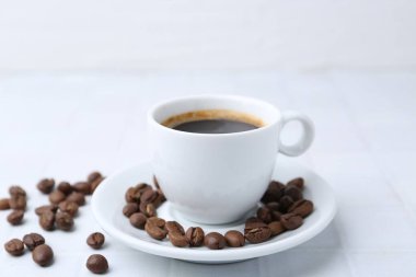 Aromatik kahve fincanda ve fasulye beyaz masada, yakın plan.