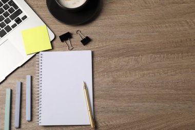 Defter, diğer kırtasiye malzemeleri, kahve ve dizüstü bilgisayar ahşap masada, düz konum. Metin için boşluk